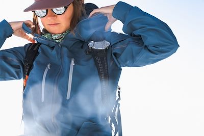 Femme en train d'ajuster sa veste dans la neige