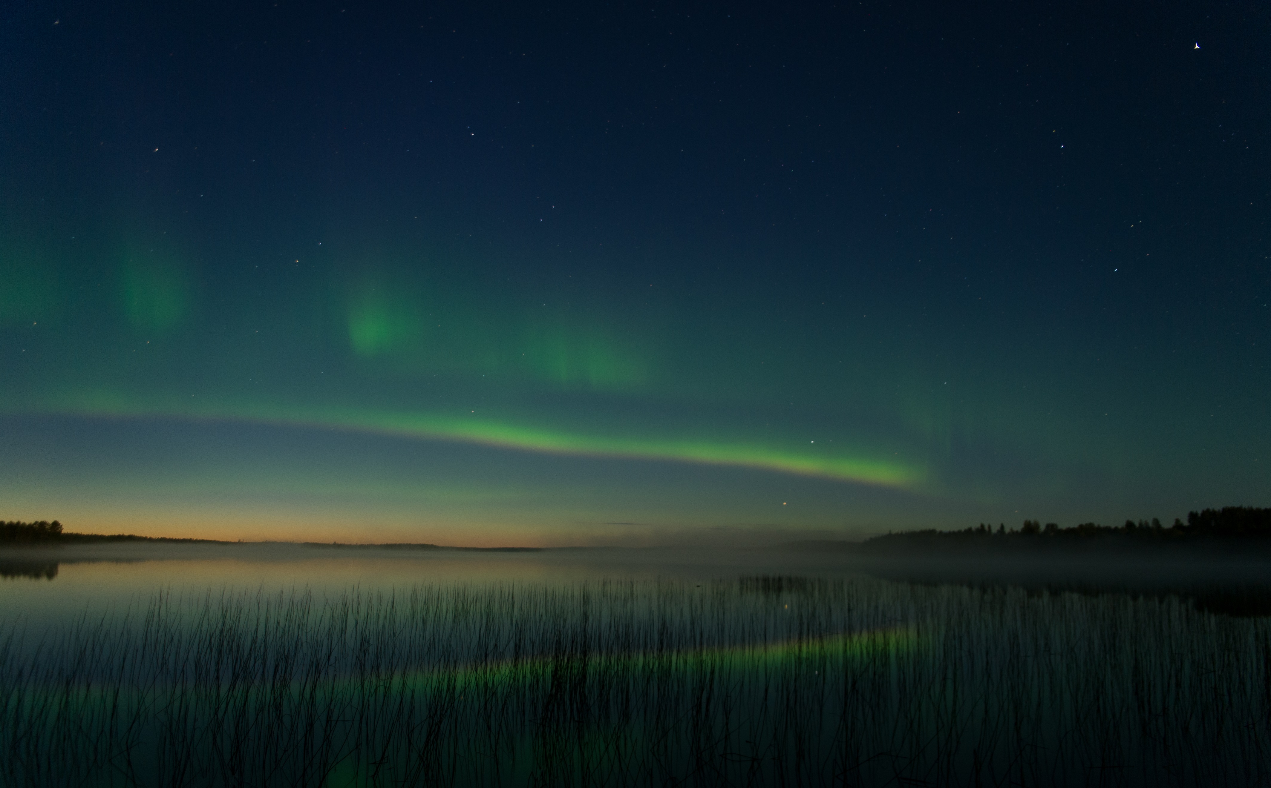 Une aurore bor&eacute;ale brille au loin au-dessus d'un des nombreux lacs de Finlande &copy;Sabrina Logeais / Ta&iuml;ga Spirit
